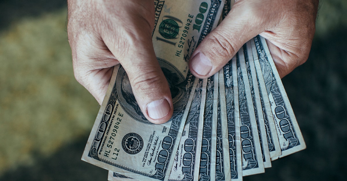 Man holding a stack of 100 dollar bills