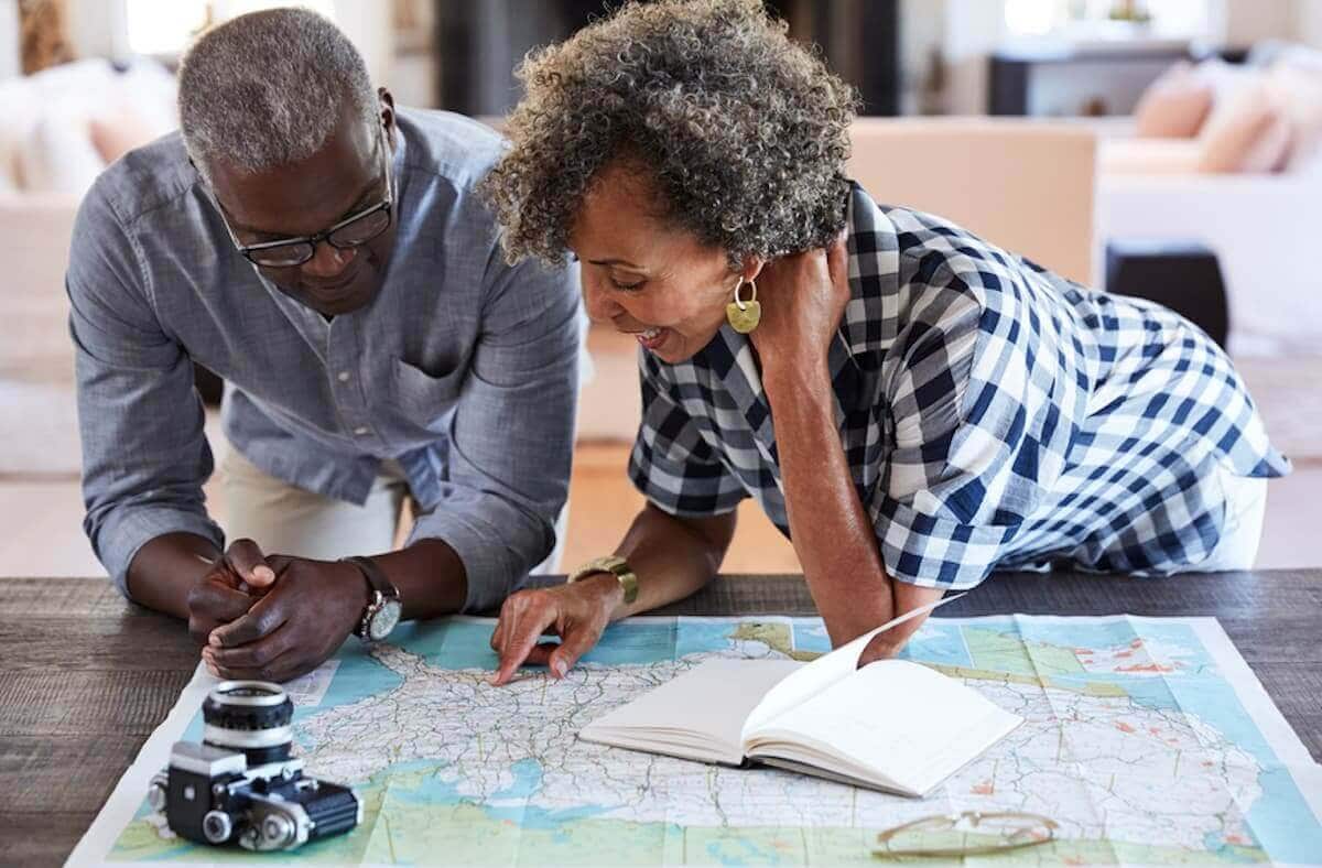 An older Black couple looks over a map.
