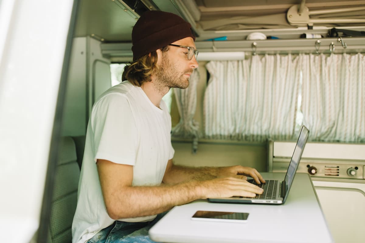 Man seated in a van working remotely on laptop