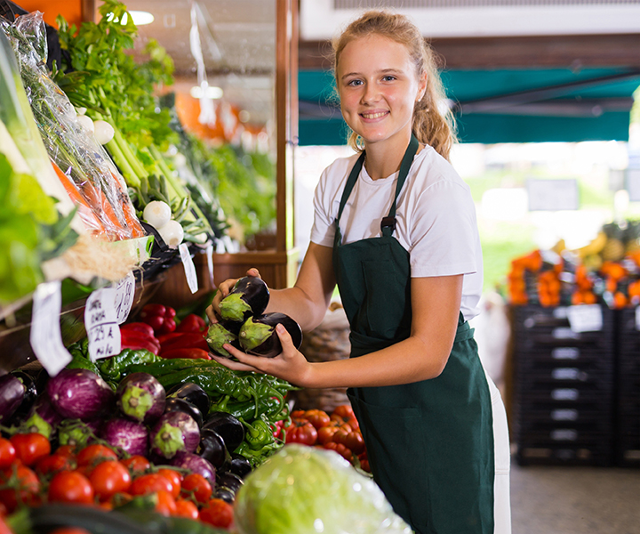 A person standing in front of a display of vegetables.