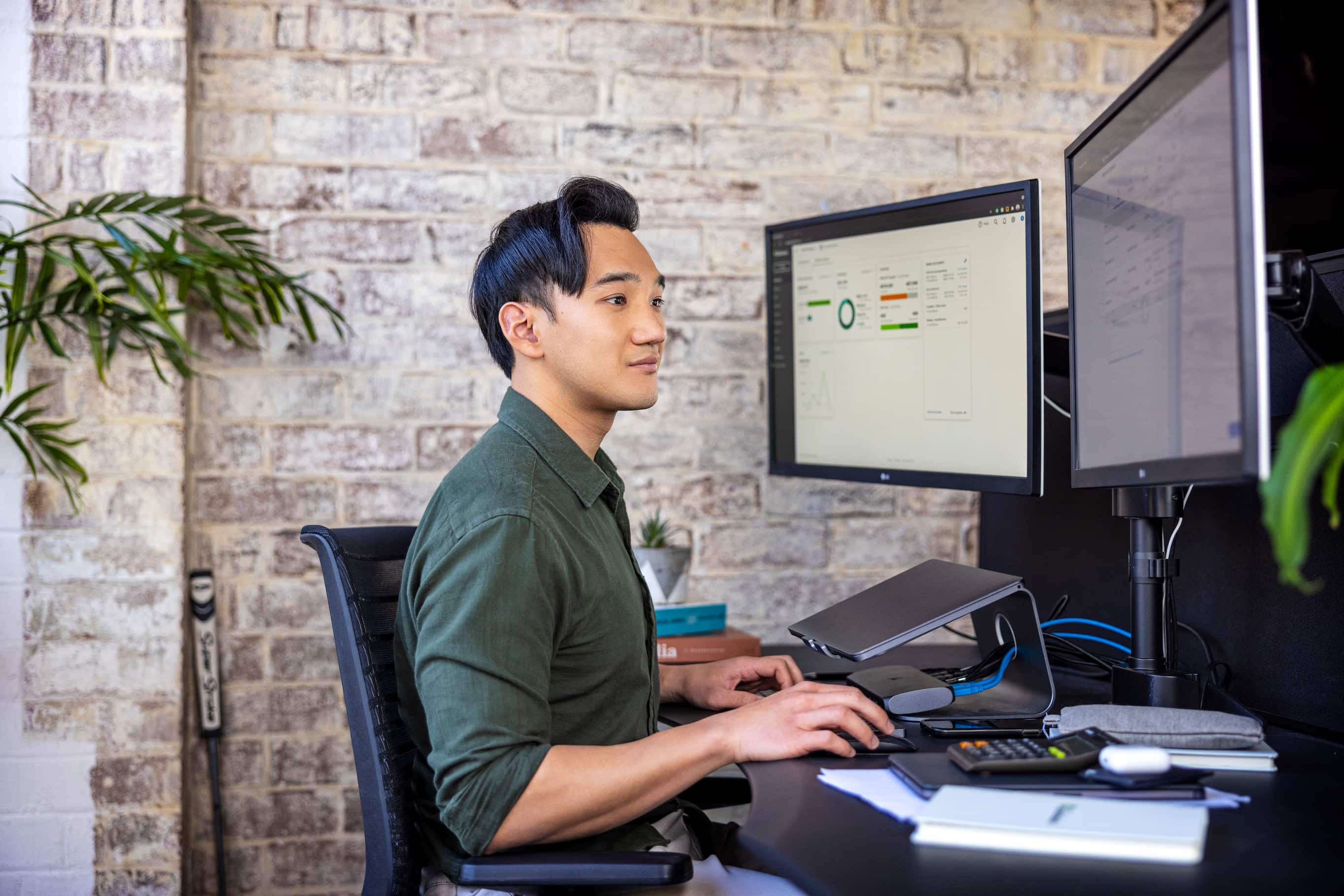 Young professional working at dual monitor desk setup