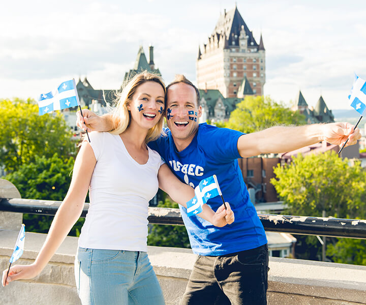 Young adults celebrating with Quebec flags outdoors