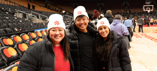 Three Raptors fans smiling court-side.