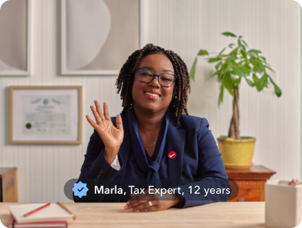 Marla, a tax expert with 12 years of experience, smiling and waving in her home office.