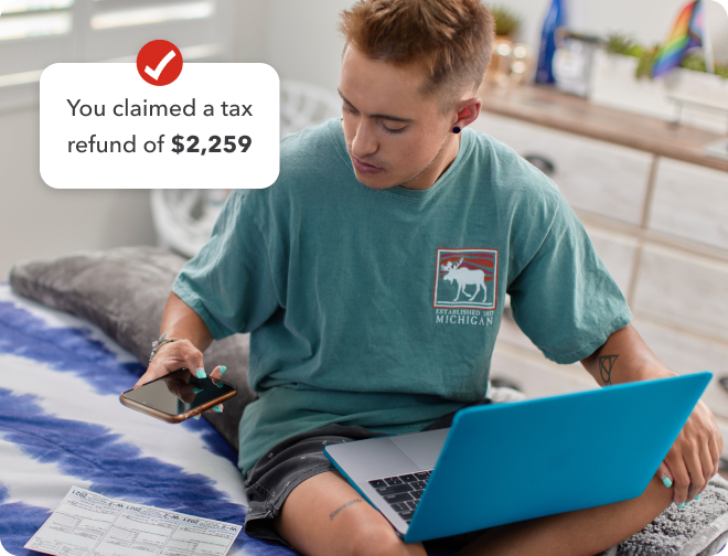 A young man sitting on his bed with a laptop while taking a picture of a tax form with his smartphone. Secondary image is of a TurboTax checkmark logo and text “You claimed a tax refund of $2,259”.