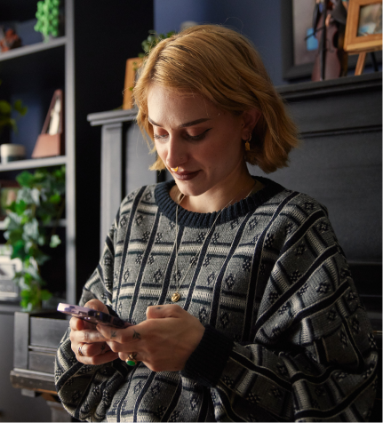 A young woman looking down at her smartphone in her home.