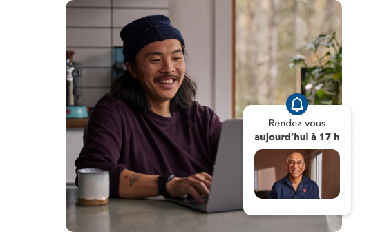 Un jeune homme sourit tout en travaillant sur son ordinateur portable chez lui. Illustration secondaire avec le message « Vous avez un rendez-vous! Aujourd’hui à 17 h ».