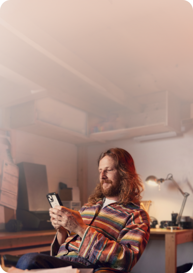 Un client de TurboImpôt travaillant sur son téléphone et sur son ordinateur portable dans son atelier.