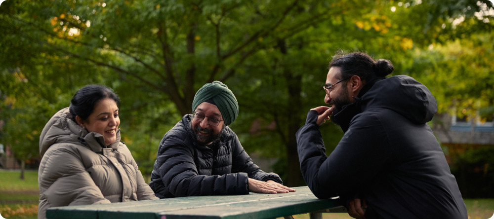 Trois personnes assises sur un banc, qui discutent et qui rient.