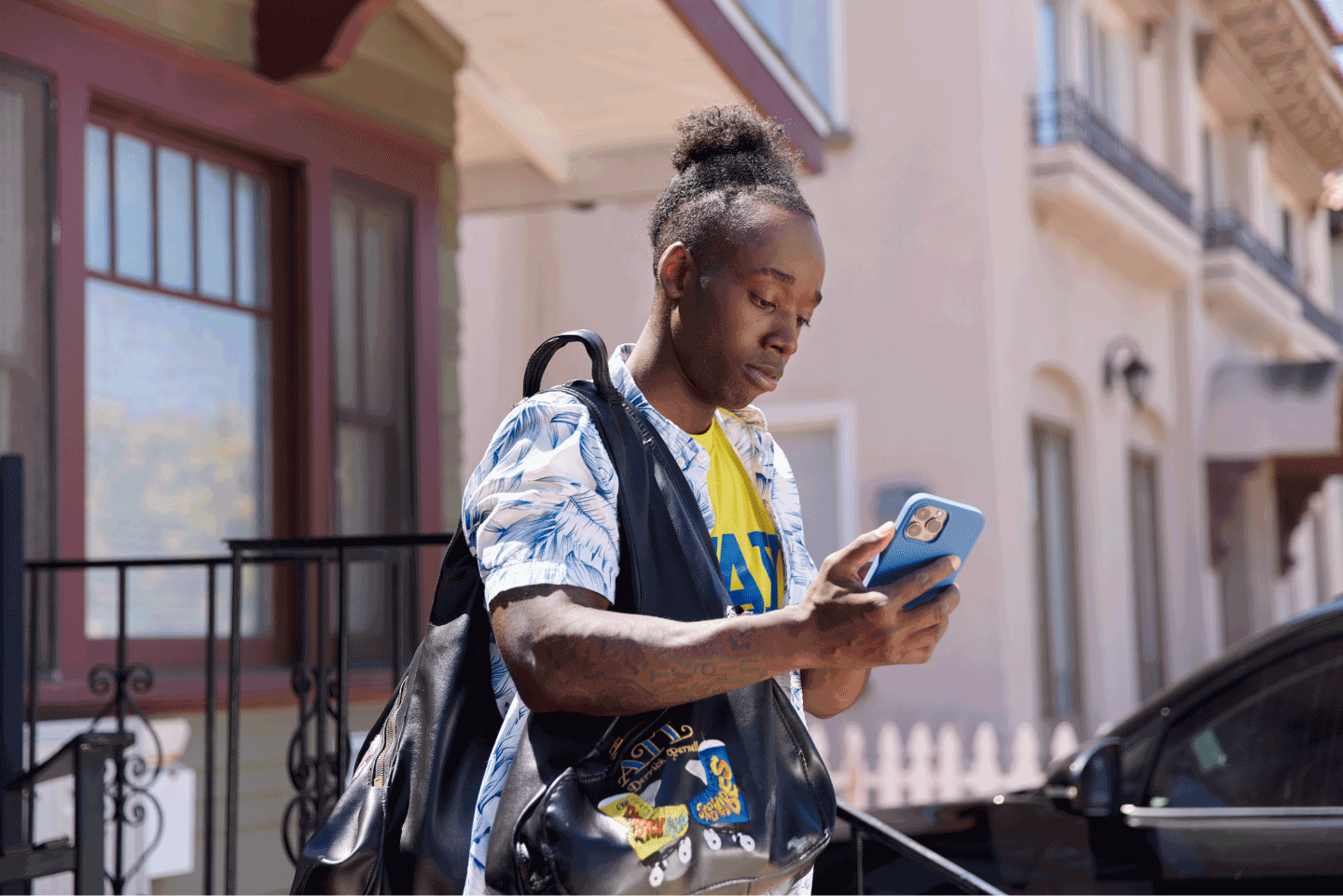 Homme noir au téléphone portant un sac à dos et qui quitte la maison