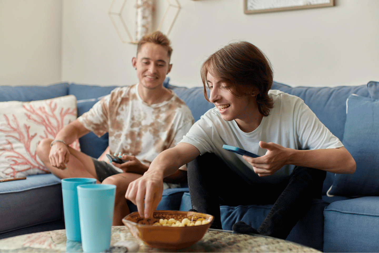 Deux jeunes hommes souriant sur leur téléphone et partageant du maïs soufflé