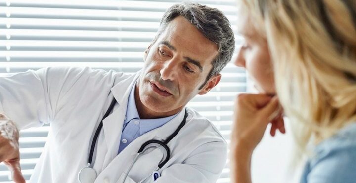 A doctor is standing next to a patient.