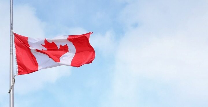 A flag flying in the air with a Canadian flag.