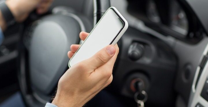 A person is sitting in a car and holding a mobile phone.