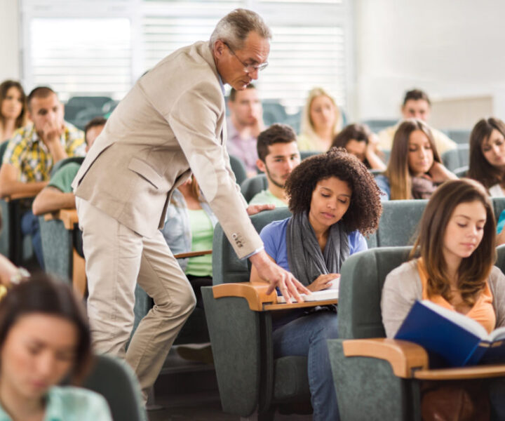 A group of students in a classroom with one student pointing at a clock.