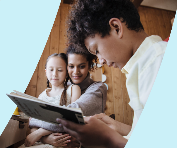 A person reading a book to two children.