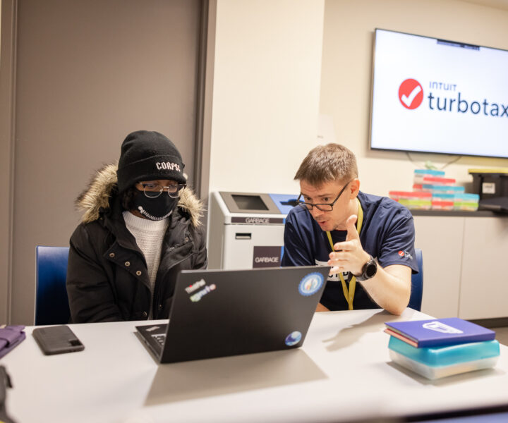 Two people sitting on a chair while looking at laptop