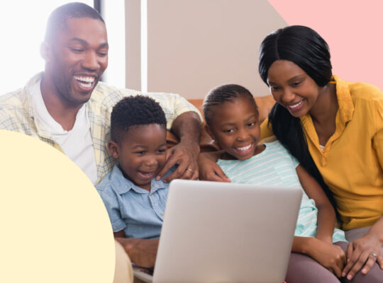 A family sitting on the couch with a laptop.