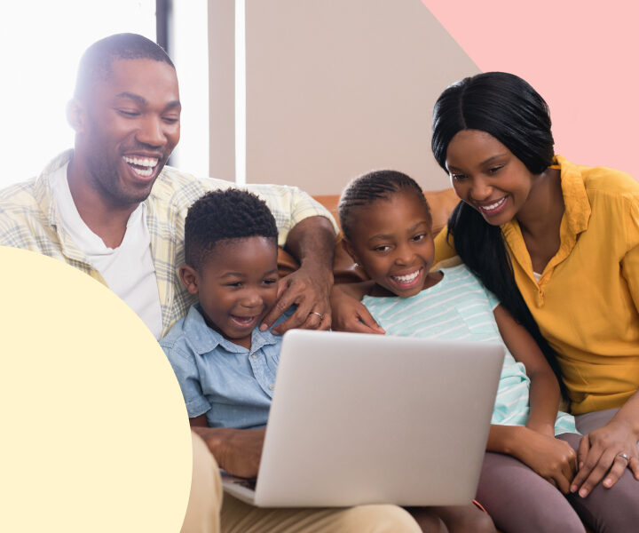 A family sitting on the couch with a laptop.