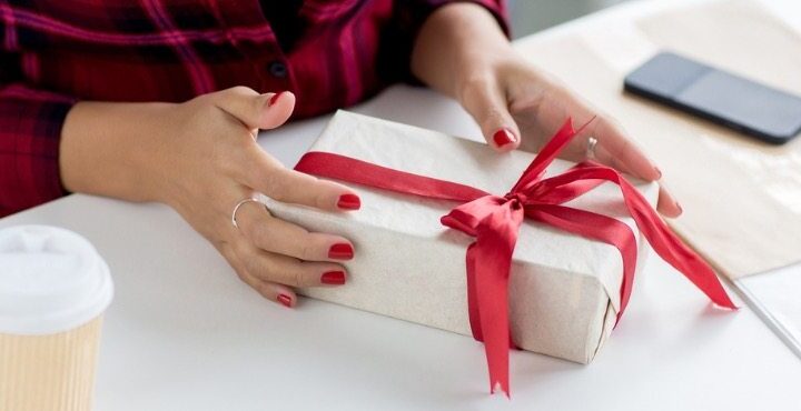 A person holding a gift box with red ribbon.