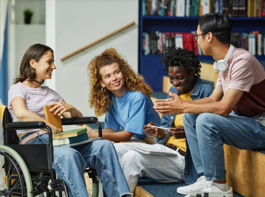 Group of young people chatting in college library.