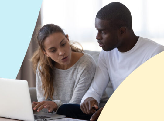 Two people are discussing while looking at a laptop.