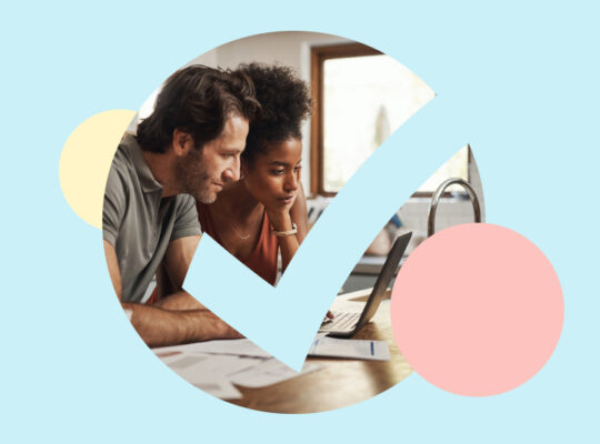 A person and person sitting at a table with a laptop.