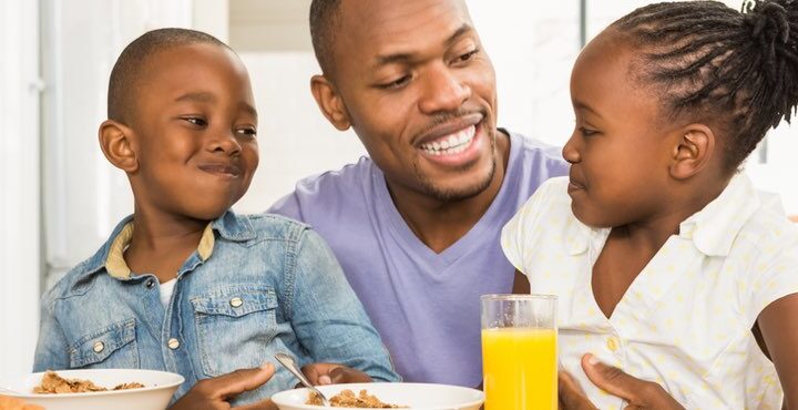 A person and two children sitting on a table.