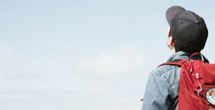 A person in a hat and sunglasses standing on a beach.