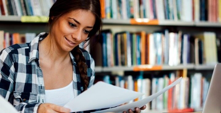 A person is looking at papers while sitting at a desk.