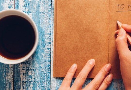 A person is writing a to do list on a table.