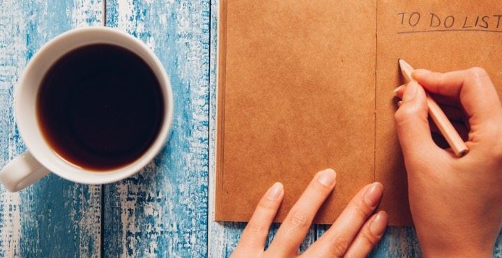 A person is writing a to do list on a table.