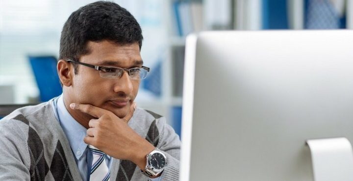 A person sitting at a desk looking at a laptop.