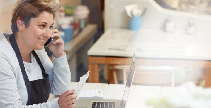 A person sitting at a desk talking on a cell phone.