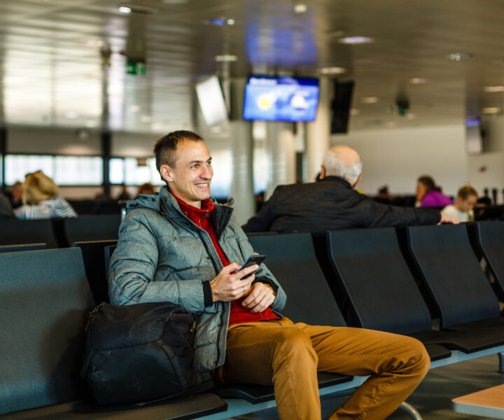 A person sitting on a bench with a bag of luggage.