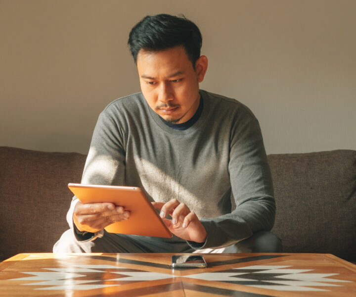 A person sitting on a couch using a laptop computer.