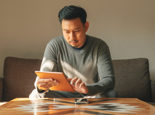 A person sitting on a couch using a laptop computer.