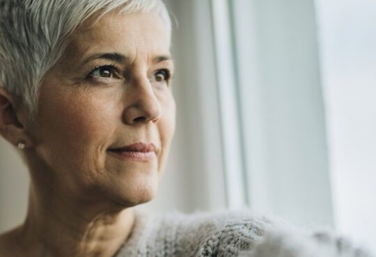 A portrait of a beautiful mature woman relaxing by the window.
