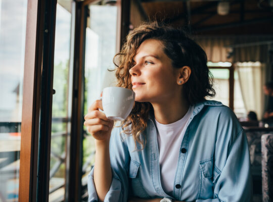 A person sitting at a table drinking a cup of coffee.