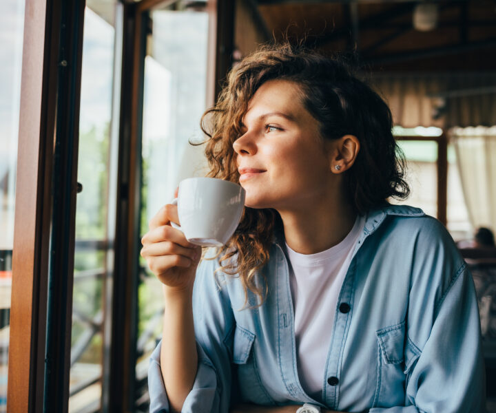 A person sitting at a table drinking a cup of coffee.