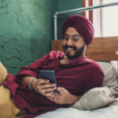 A person in a red shirt is looking at a cell phone.