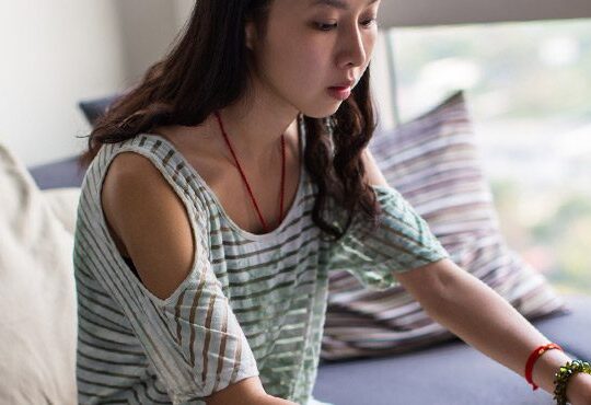 A person sitting on a bed with a laptop.