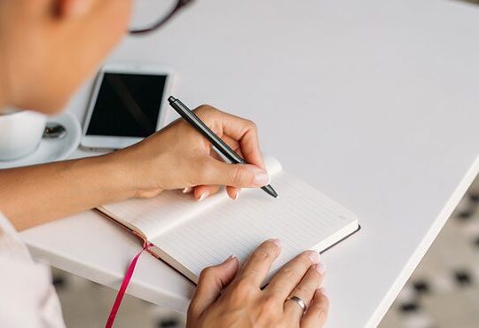 A person holding a pen and a notebook.