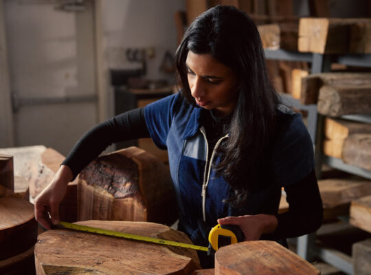 A person is measuring a wooden log.