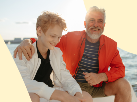 A person and person sitting on a bench smiling.