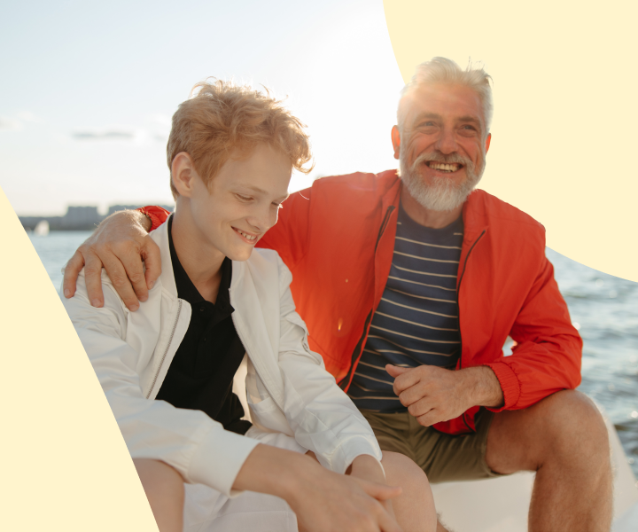 A person and person sitting on a bench smiling.