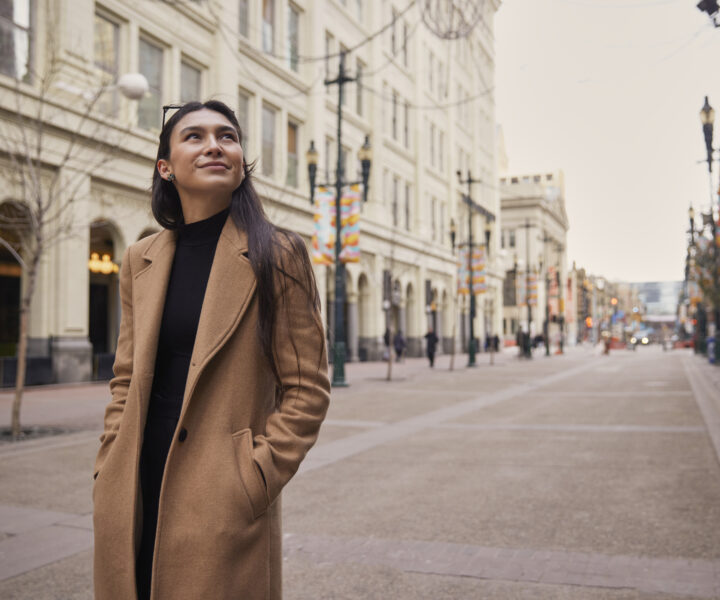 A woman is wearing a coat and walking on the street