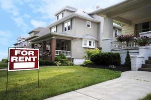 A picture of house with a sign board "For Rent".