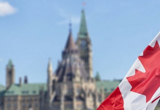 A Canadian flag flying in front of a Canadian flag.