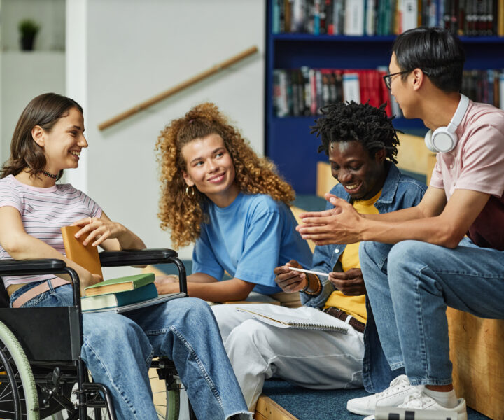 Group of young people chatting in college library.